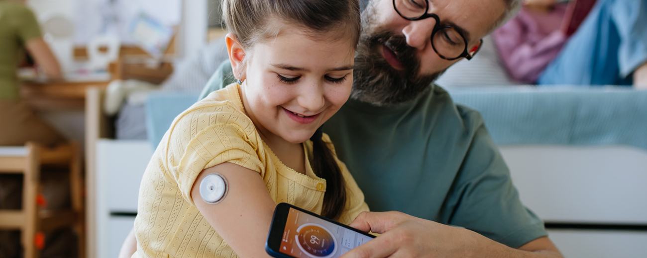 Person sitter i köket och tittar ner på sin mobiltelefon