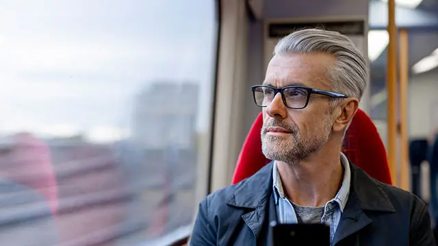 Person sitter framför en dator vid ett köksbord hemma och tittar ut