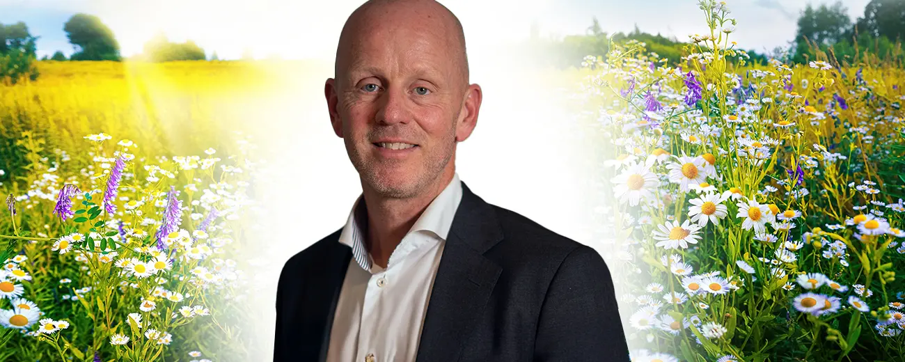 Staffan Johansson står i kostym i kontorslandskap och tittar leendes in i kameran.