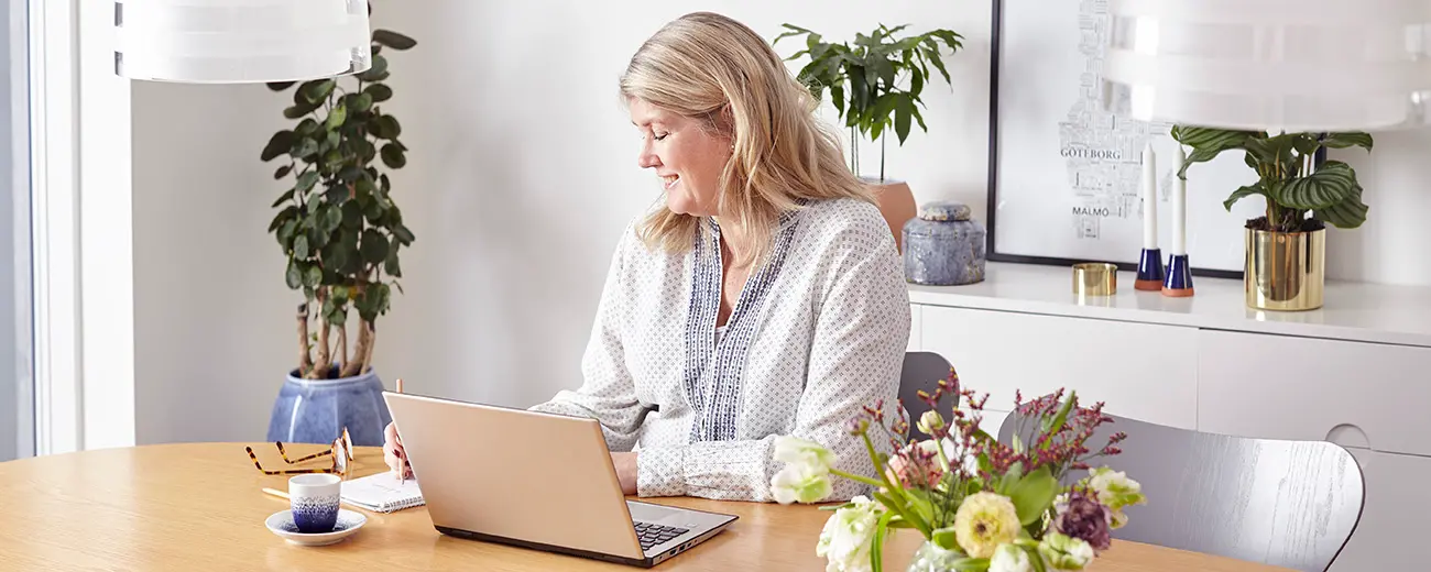 Person sitter vid köksbordet och arbetar framför dator