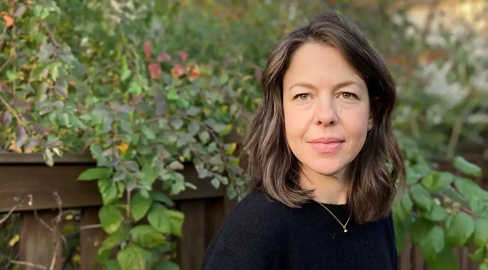 Psykologen Sara Brunt står utomhus framför ett träd, iklädd svart, och tittar in i kameran