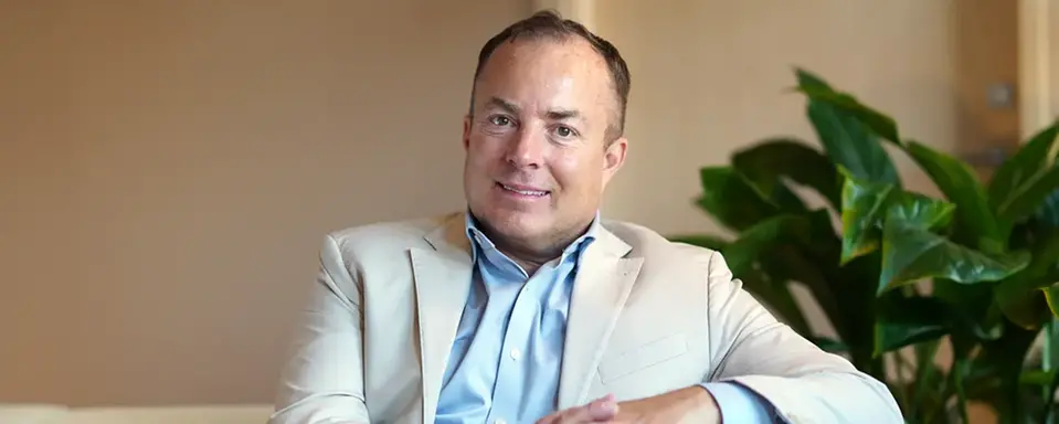 Fredrik Bengtsson, psykolog, sitter i ljus miljö iklädd ljus kavaj och tittar leende in mot kameran