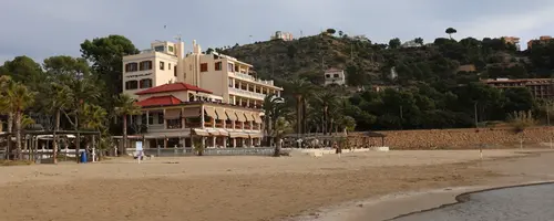 Barn med hårløst hode går hånd i hånd med helsearbeider i lys sykehuskorridor sett bakfra.